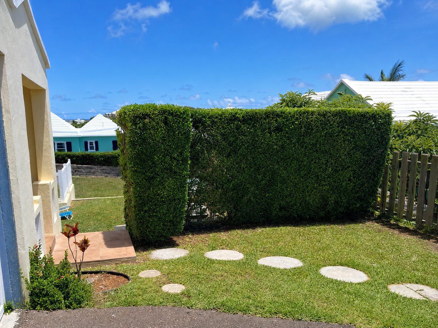 Trimmed hedge and finished lawn with stepping stones at a Bermuda home